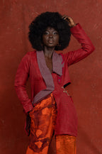 Person wearing a red coat and orange pants against a red background