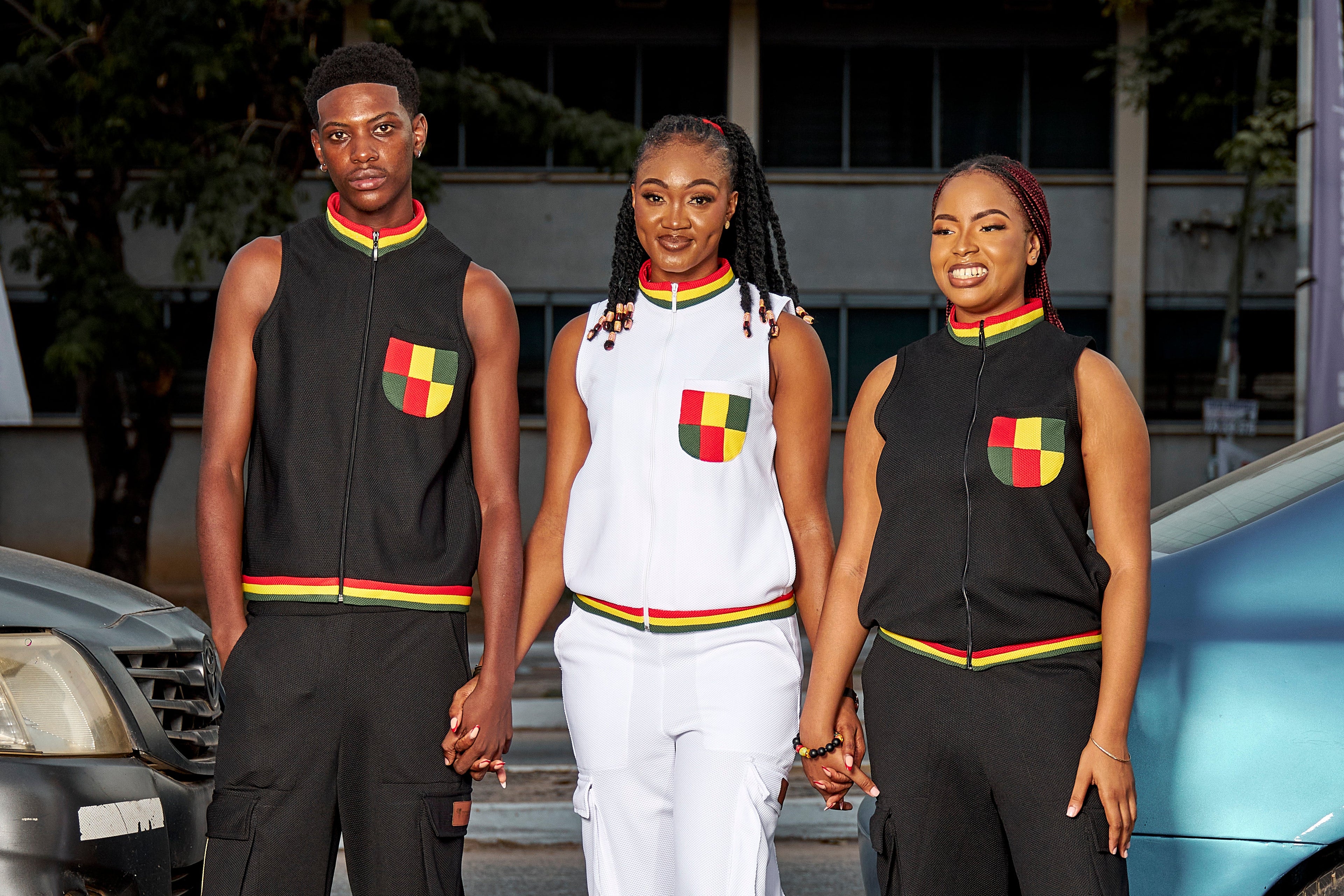 Three models in colourful Africa United Unisex Tops and Cargo Pants, holding hands in an urban setting