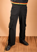 Man wearing a black sleeveless jacket with colorful accents and black cargo pants on a beige background